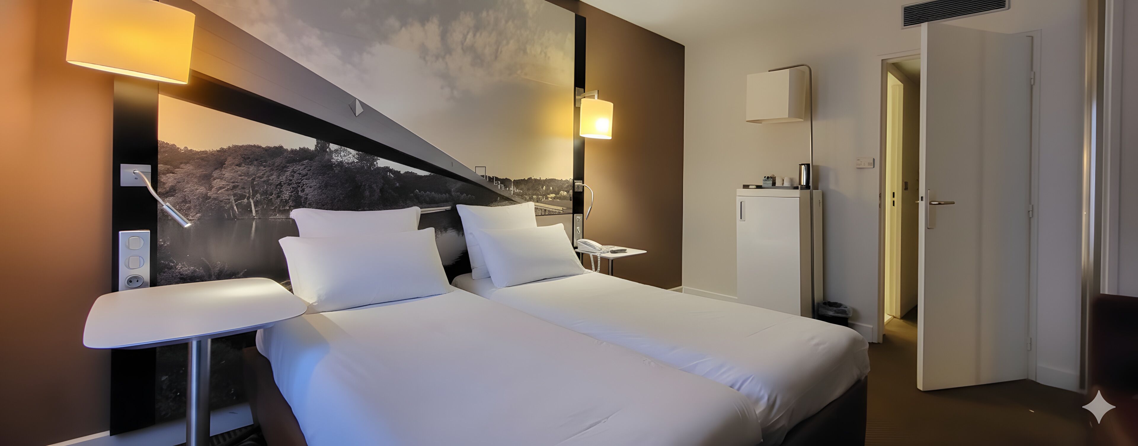 A hotel room with two beds, a desk, a phone, and a view of a landscape through the window.