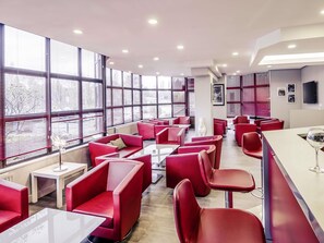 Un restaurante moderno con asientos rojos, ventanas amplias y un televisor de pantalla plana.
