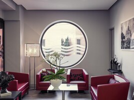 Un interior moderno con un ventanal redondo, sofás rojos, una mesa de centro blanca y una orquídea en maceta.