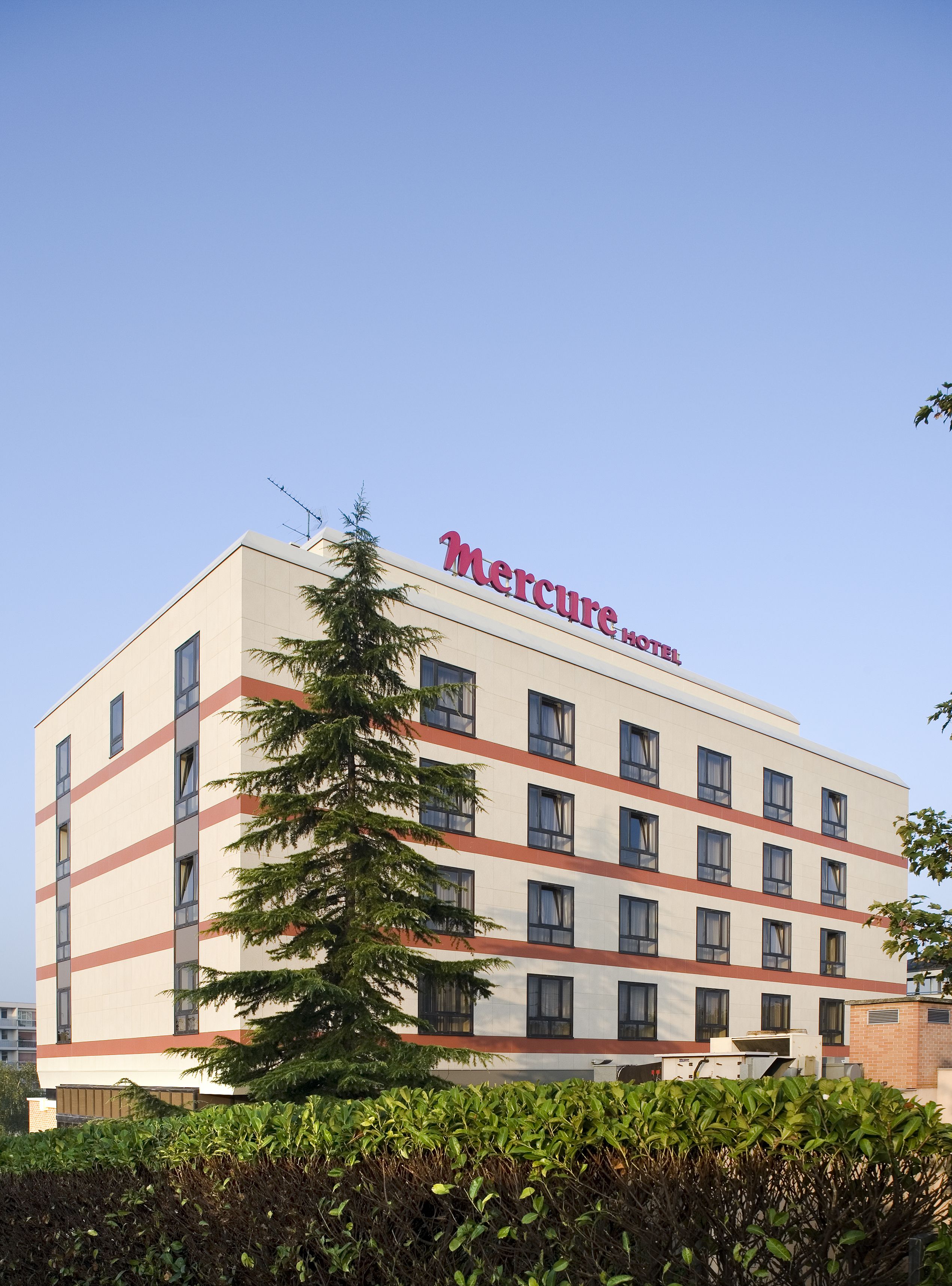 Un hotel Mercure con diseño moderno, que presenta un techo plano y varias ventanas.