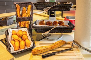 Un bufé de desayuno con panes y pasteles variados en cestas de mimbre.