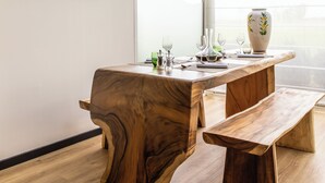 A modern dining area with a wooden table and bench, a vase, and a television on the wall. - ibis Styles Chartres Sud Barjouville (Barjouville)