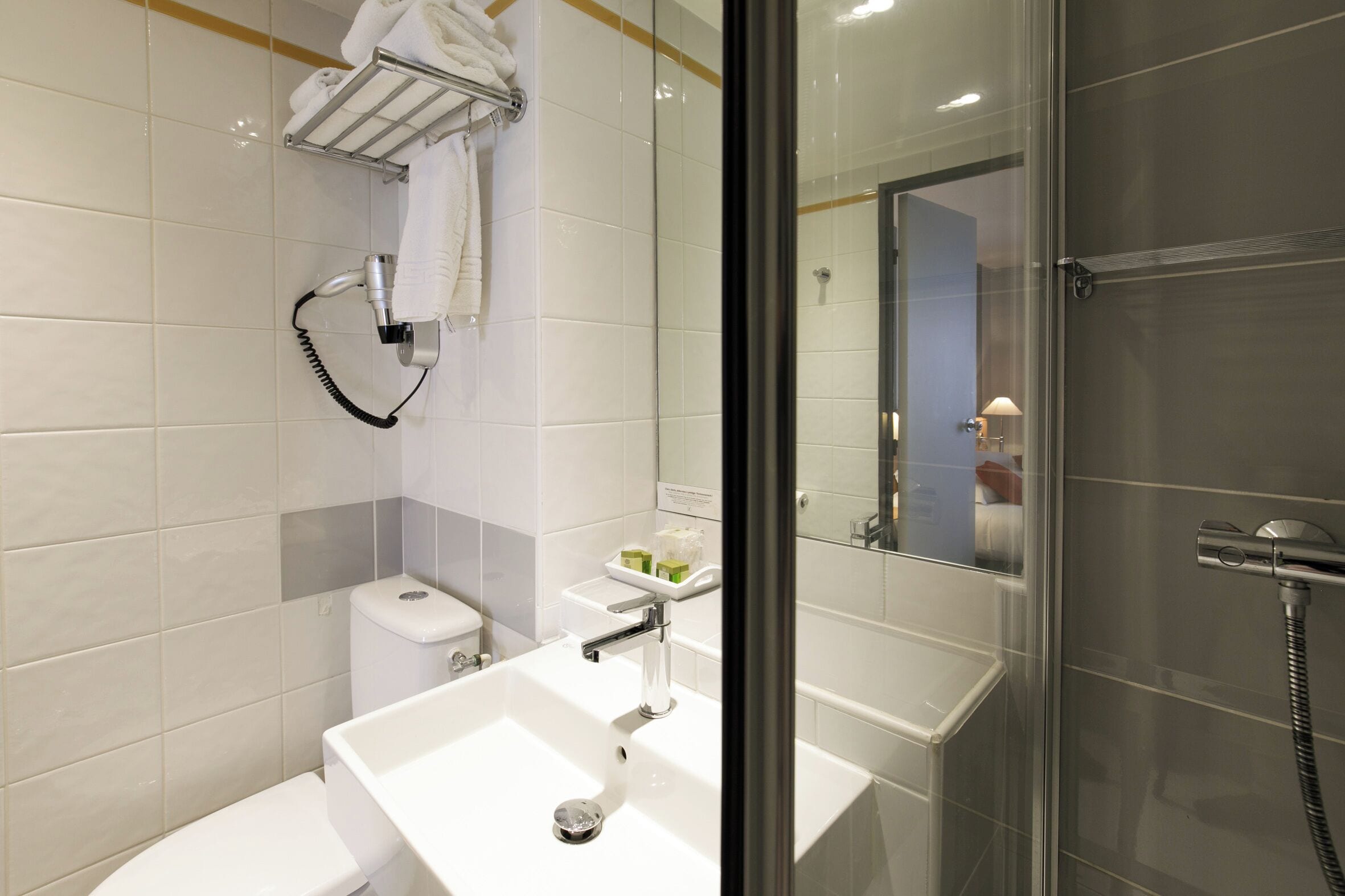 A modern bathroom with a white sink, a glass shower enclosure, and a towel rack.