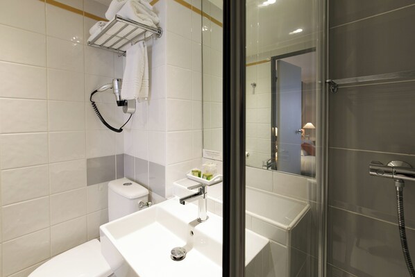 Un baño moderno con un lavamanos blanco, una mampara de ducha de vidrio y un perchero para toallas.