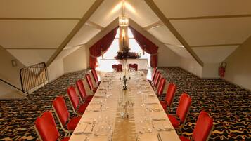 A conference room with a long table set for a meeting, red chairs, and a chandelier.