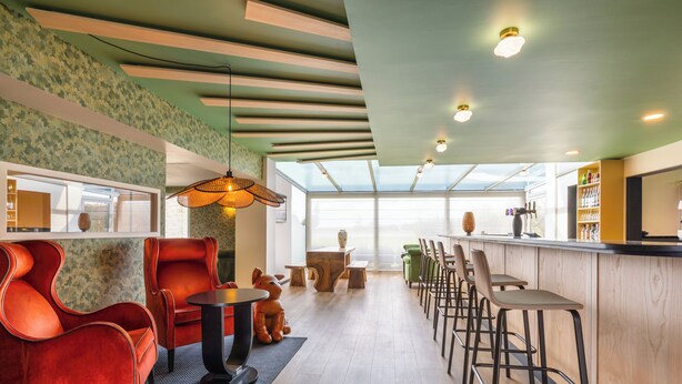 A modern interior with a bar area, seating, and a large window providing natural light. - ibis Styles Chartres Sud Barjouville (Barjouville)
