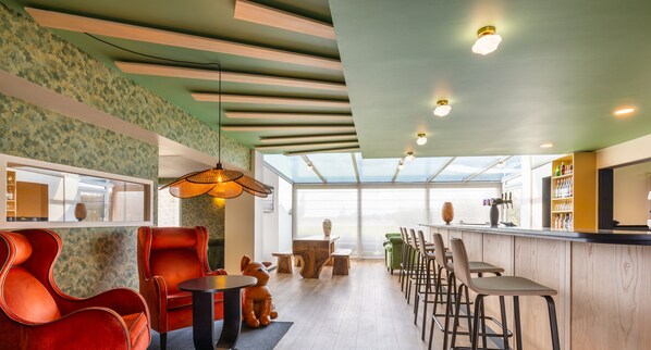 A modern hotel interior with a bar area, seating, and a view through large windows.