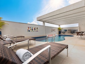 Et tagområde med pool, liggestole og en pergola.
