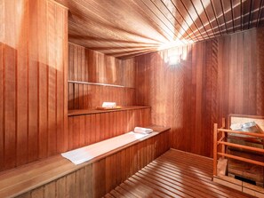A sauna room with wooden walls and benches, a shelf with towels, and a metal rack. - Mercure Sao Paulo Moema Hotel (São Paulo)