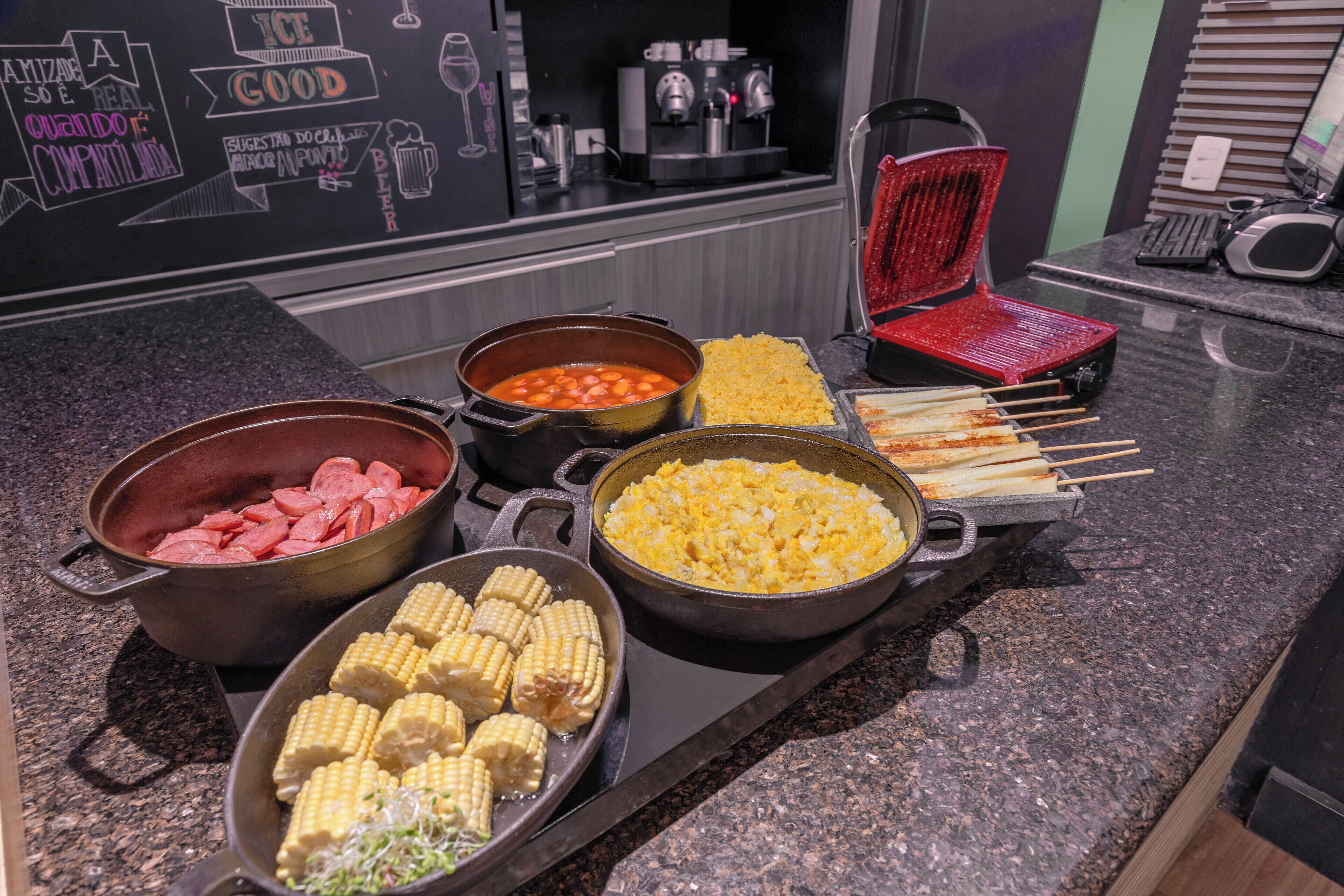 Een buffet met diverse gerechten, waaronder maïs, gepofte maïs en spiesjes.