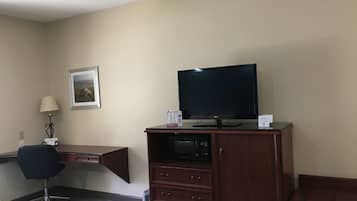 Una habitación de hotel con un escritorio de madera, televisión, una silla y una cama.