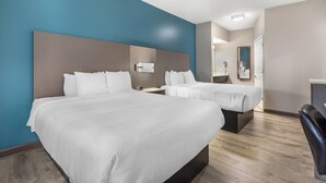 A hotel room with two beds, a desk, and a chair.