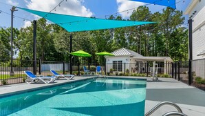 A swimming pool with blue lounge chairs and a covered pavilion.