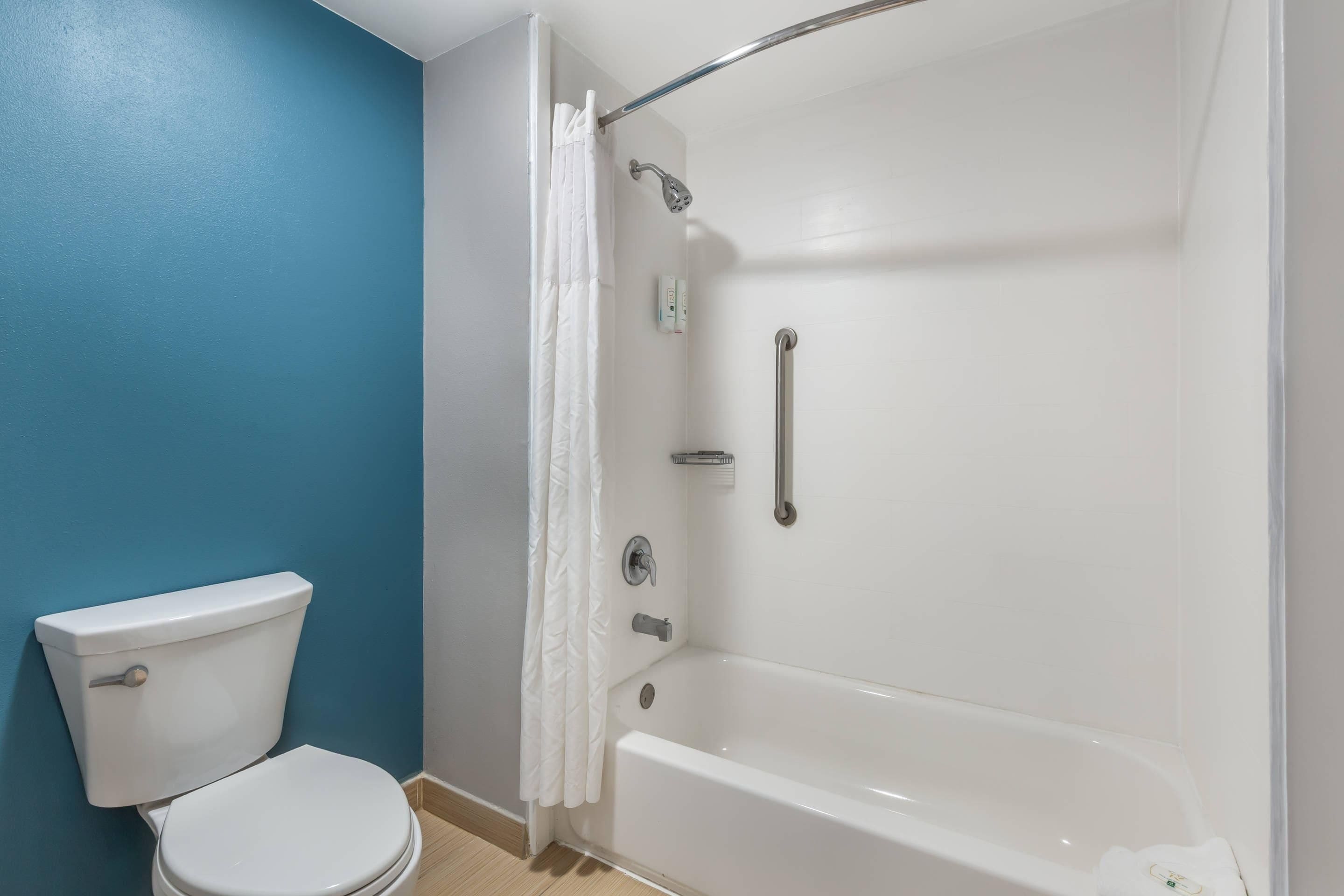 Un baño con inodoro blanco, bañera y ducha con cortina.