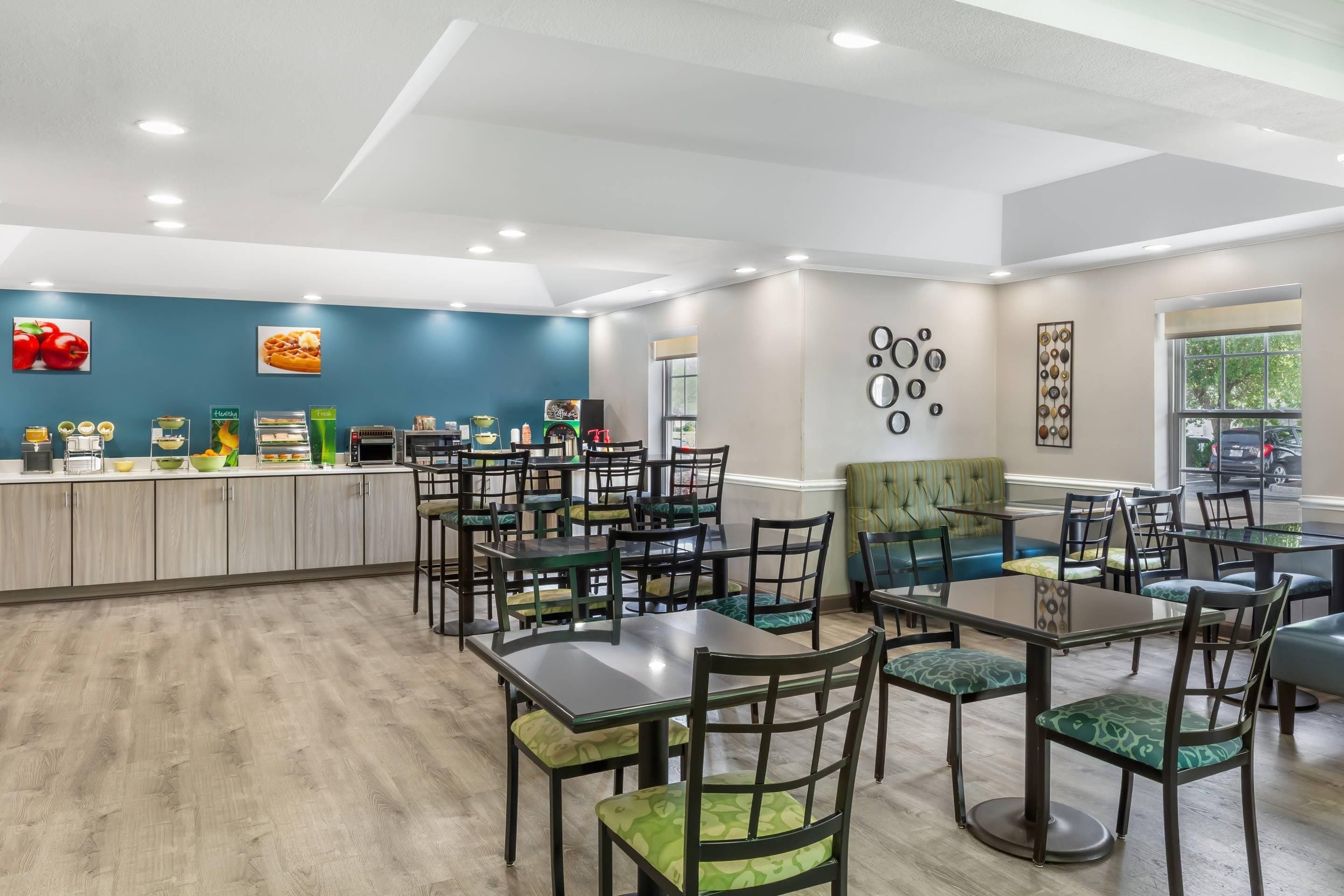A dining area with multiple tables and chairs, a counter with food items, and a wall with circular decorations.