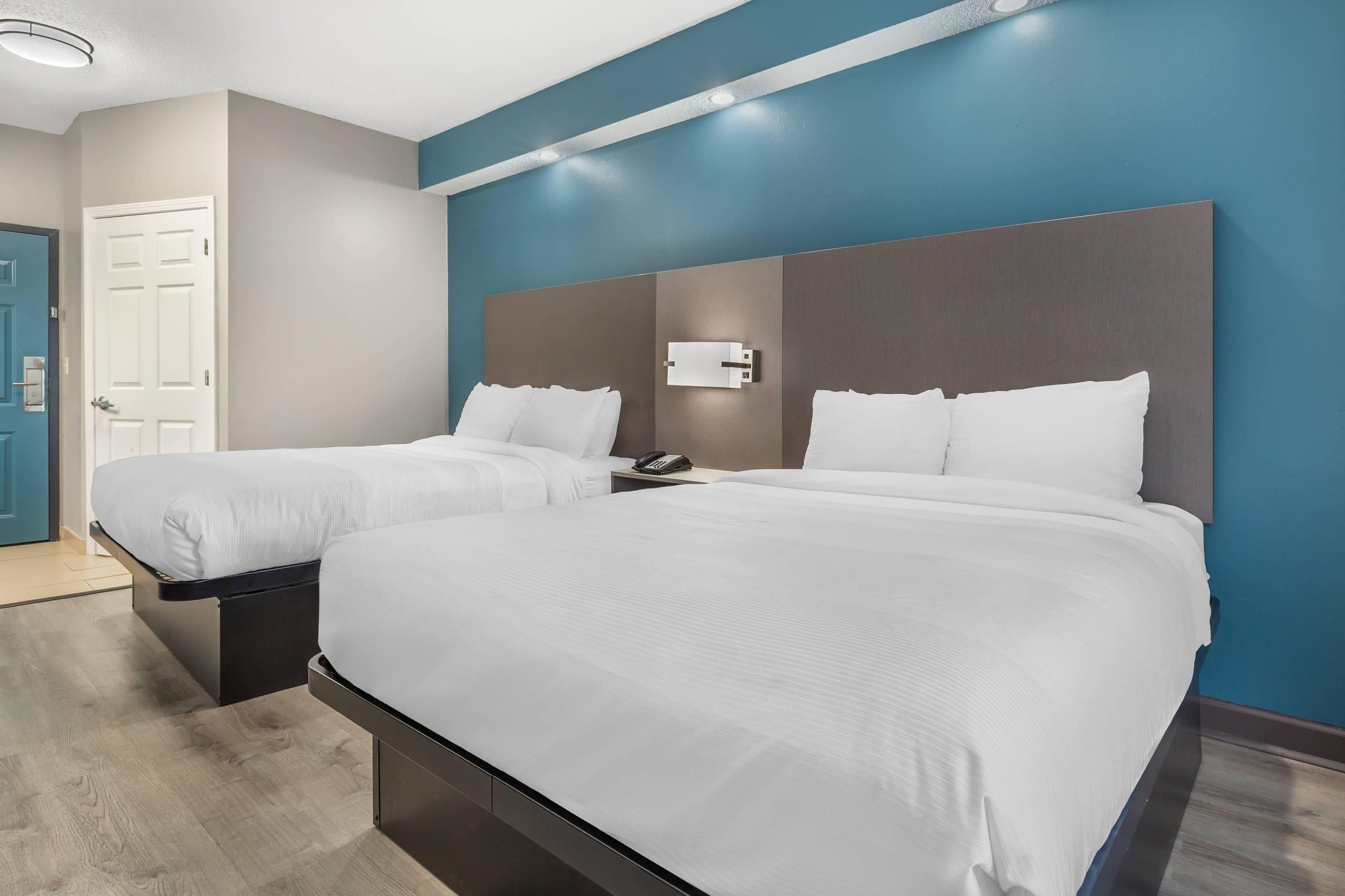 Une chambre d’hôtel avec deux lits, une porte et un téléphone fixé au mur.
