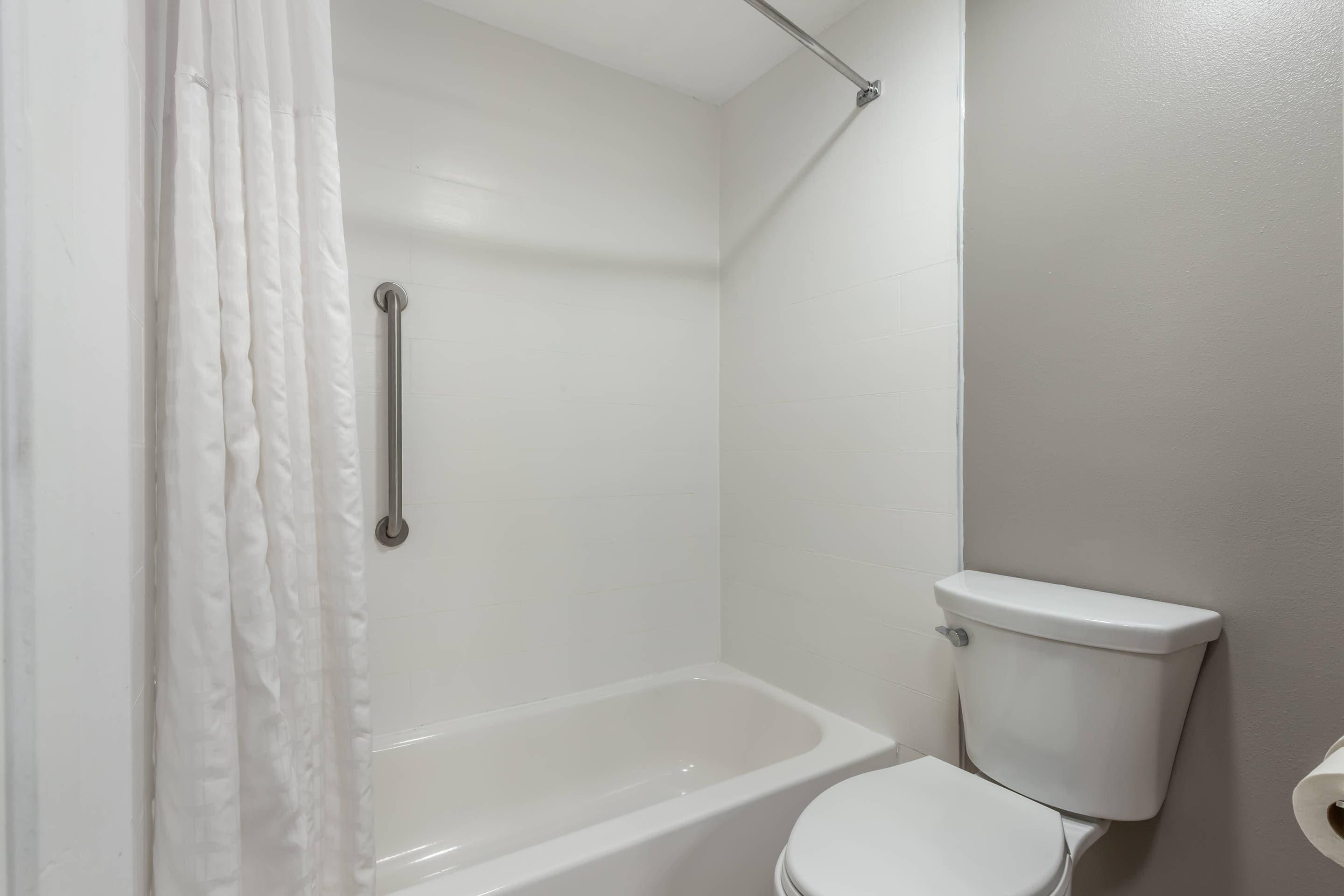 A bathroom with a bathtub, toilet, and a shower curtain.