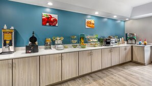 A breakfast bar with various food items and a waffle maker.