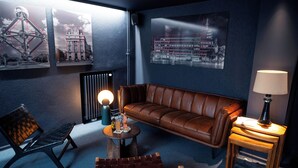 A cozy room with a brown leather sofa, a small wooden table with a lamp, a black metal chair, and a radiator. - Queen Anne Hotel (Brussels)