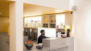 A reception area with a counter, shelves with magazines, and a desk. - Queen Anne Hotel (Brussels)