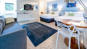 Una camera d'albergo moderna con divano, letto, scrivania e sedia, e televisione.