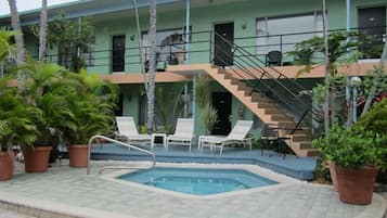 A pool area with lounge chairs and a staircase leading to an upper level.