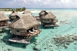 Bungalows sobre el agua con techos de paja, pasarelas de madera y aguas turquesas cristalinas.