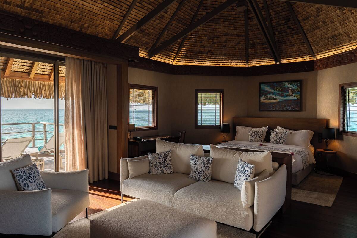 Une chambre avec un lit, un canapé, un bureau et une vue sur la mer.