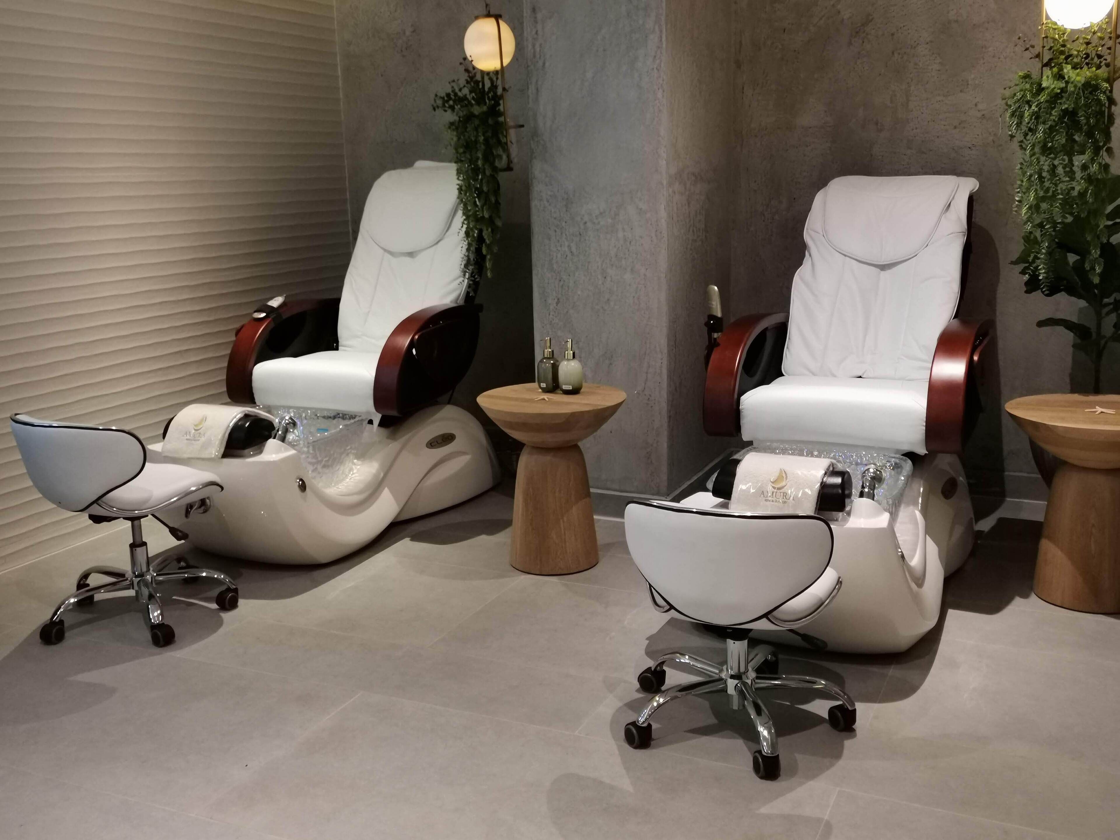 Un área de spa con dos sillones de masaje, una bañera para pies y una pequeña mesa con una botella.