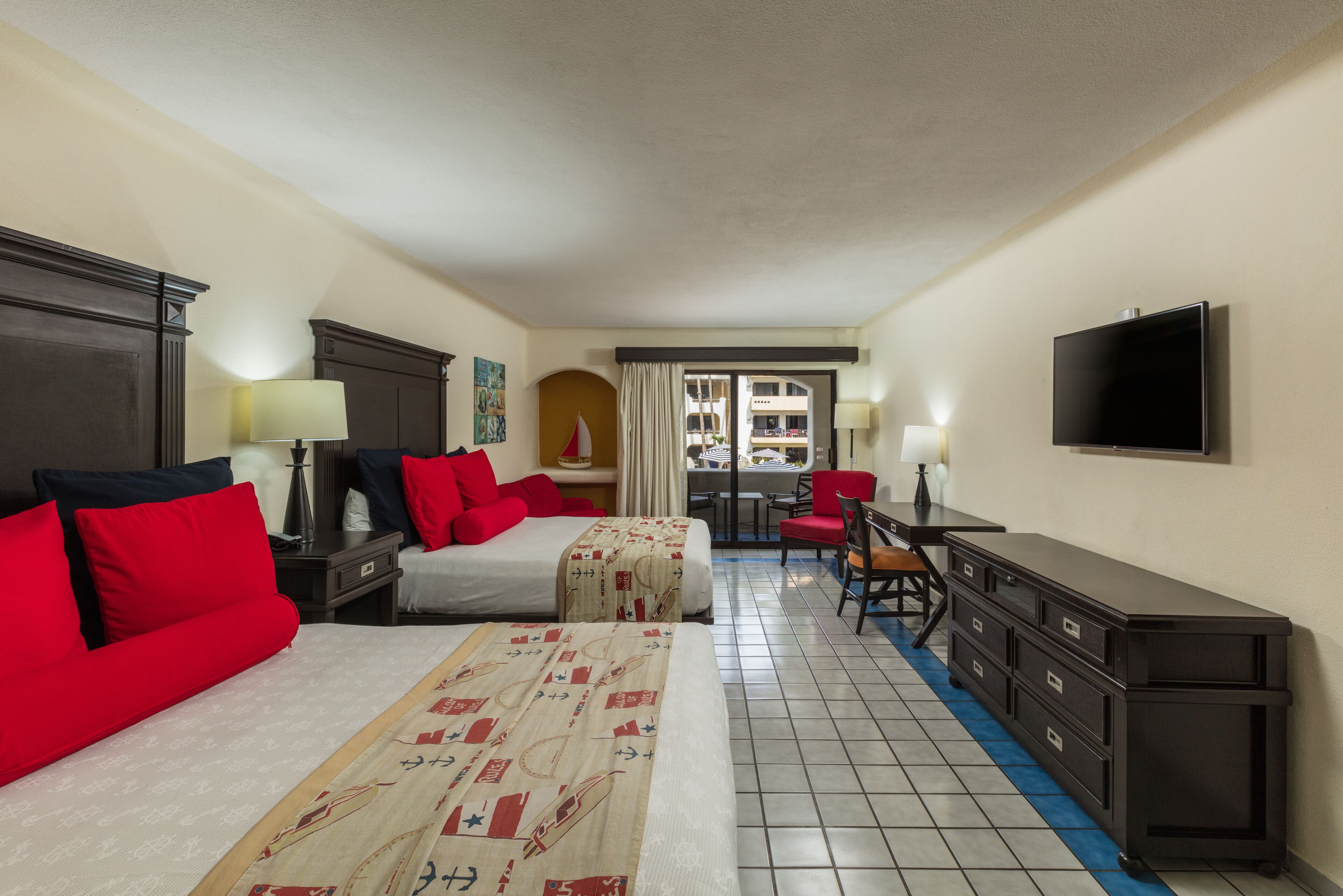 Habitación de hotel con dos camas, un escritorio, una silla, un televisor y vista al exterior.