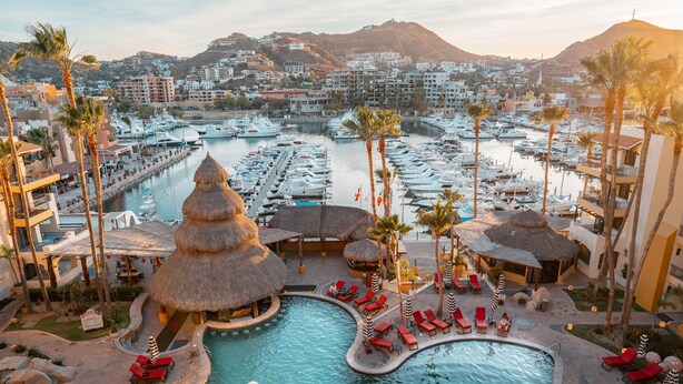 A resort with multiple swimming pools, palm trees, and a marina with boats. - Marina Fiesta Resort & Spa (Cabo San Lucas)