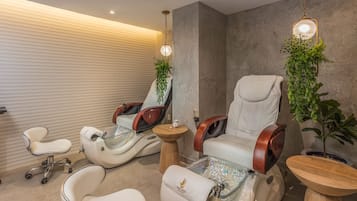 A modern spa room with massage chairs, a small table, and potted plants.