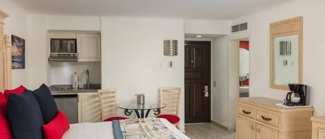 Una habitación de hotel con cama, kitchenette, mesa de comedor y espejo.