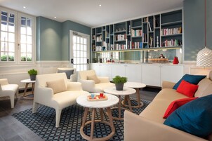 Un salon moderne comprenant un canapé, des fauteuils, une table basse et une bibliothèque.