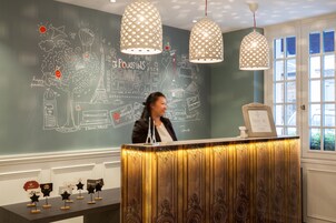 Un comptoir d'accueil avec un mur noir sur lequel sont dessinés des gribouillages et du texte, deux lampes suspendues et une fenêtre offrant une vue.