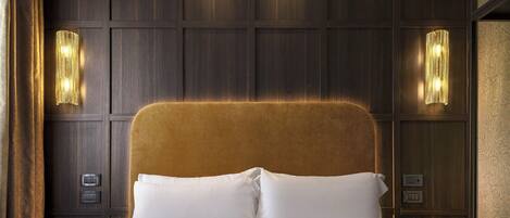 A hotel room with a large bed, two bedside tables, and wall-mounted lighting.