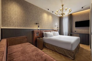 A modern hotel room with a large bed, a seating area, a television, and a patterned wall. - Hotel Atmosphere (Venice)
