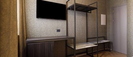 A room with a bunk bed, a flat-screen TV mounted on the wall, a desk, and a door.