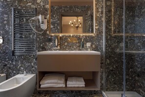 Un baño moderno con una bañera independiente, un tocador con espejo, un perchero y un box de ducha.