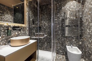 A modern bathroom with a marble backsplash, a round sink, a glass shower enclosure, and a bidet. - Hotel Atmosphere (Venice)