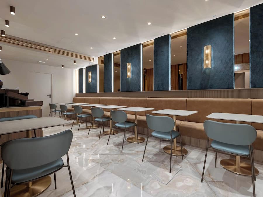 Un intérieur de restaurant moderne, avec un sol en marbre, des aménagements pour les places assises et une décoration contemporaine.