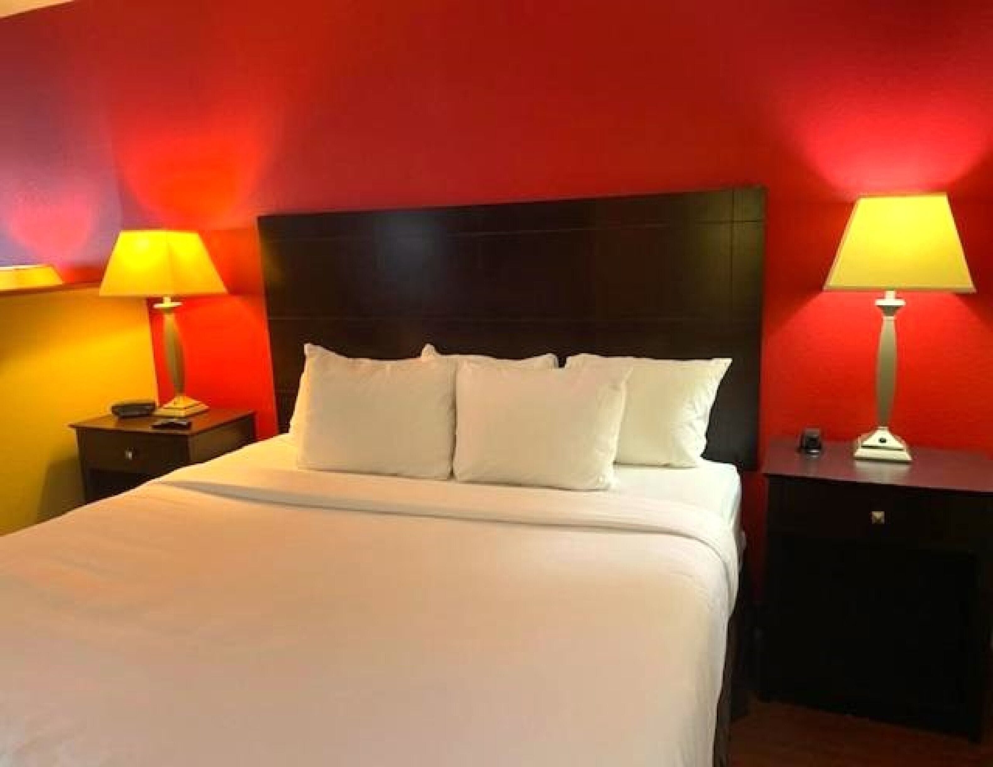Ein Hotelzimmer mit einem großen Bett, zwei Nachttischen und roten Wänden.