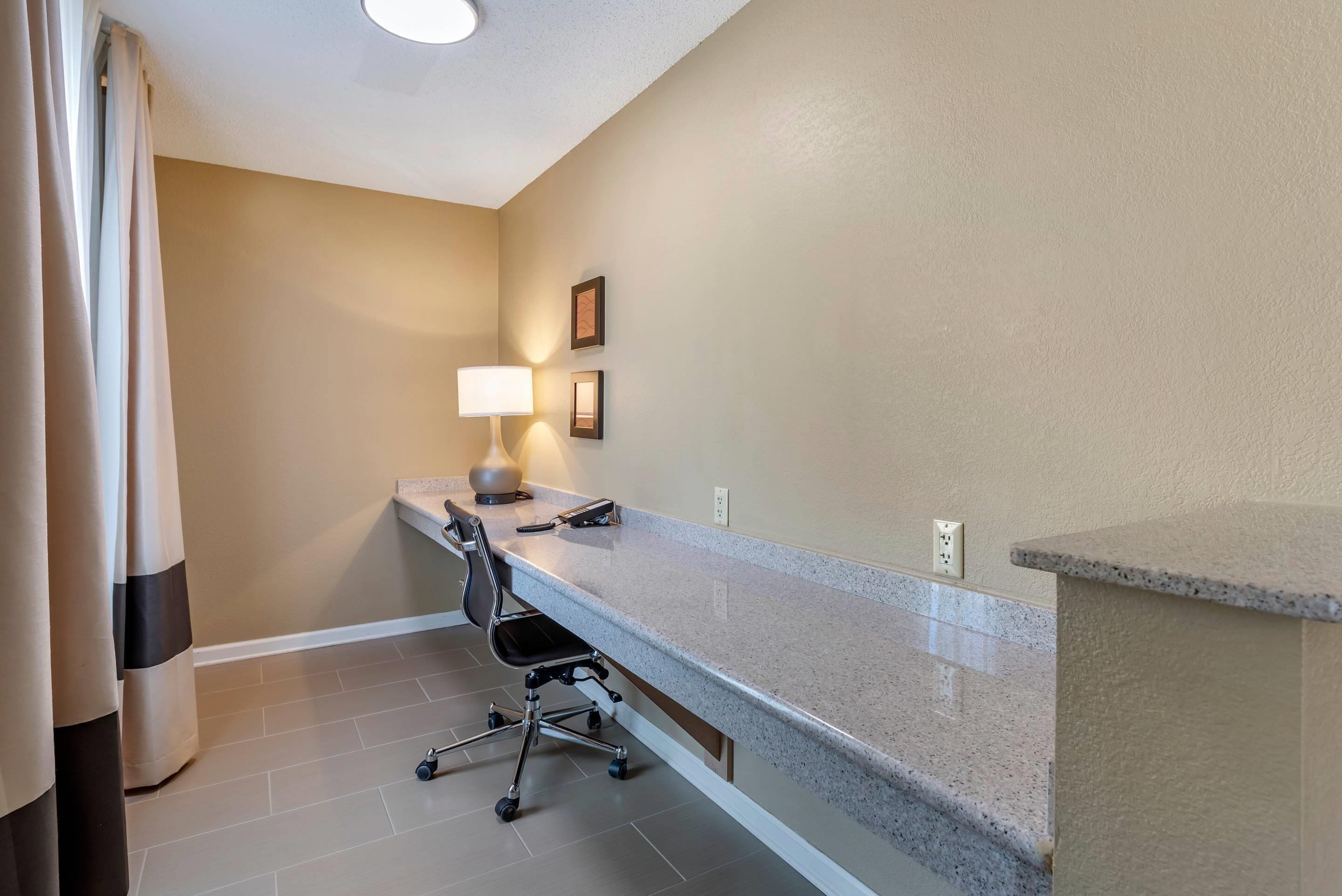 A hotel bathroom with a shower, a toilet, a sink, and a chair.