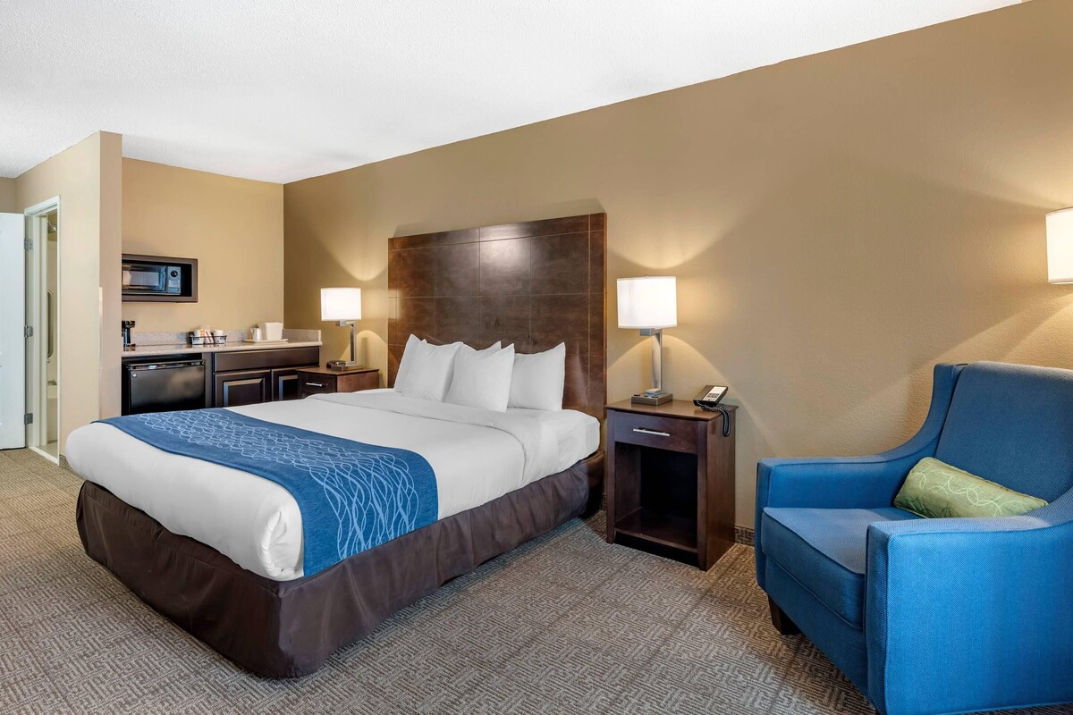 Une chambre d’hôtel avec un grand lit, des tables de chevet, un bureau, une chaise et un four à micro-ondes.