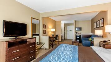 Una habitación de hotel con televisión, escritorio, kitchenette y cama.