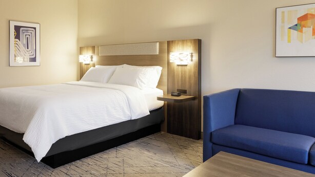 A hotel room with a bed, bedside table, and a blue sofa. - Holiday Inn Express Castro Valley - I-580 by IHG (Castro Valley)