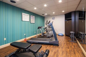 A fitness center with exercise equipment, a wall clock, and a sign indicating the center's name.