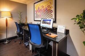 A hotel reception desk with a computer, chairs, a lamp, and a plant. - Holiday Inn Express Castro Valley - I-580 by IHG (Castro Valley)