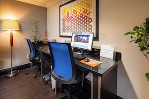 Un mostrador de recepción de hotel con computadora, sillas, lámpara y planta.