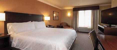 A hotel room with a large bed, a desk, a chair, a television, and a window with curtains.